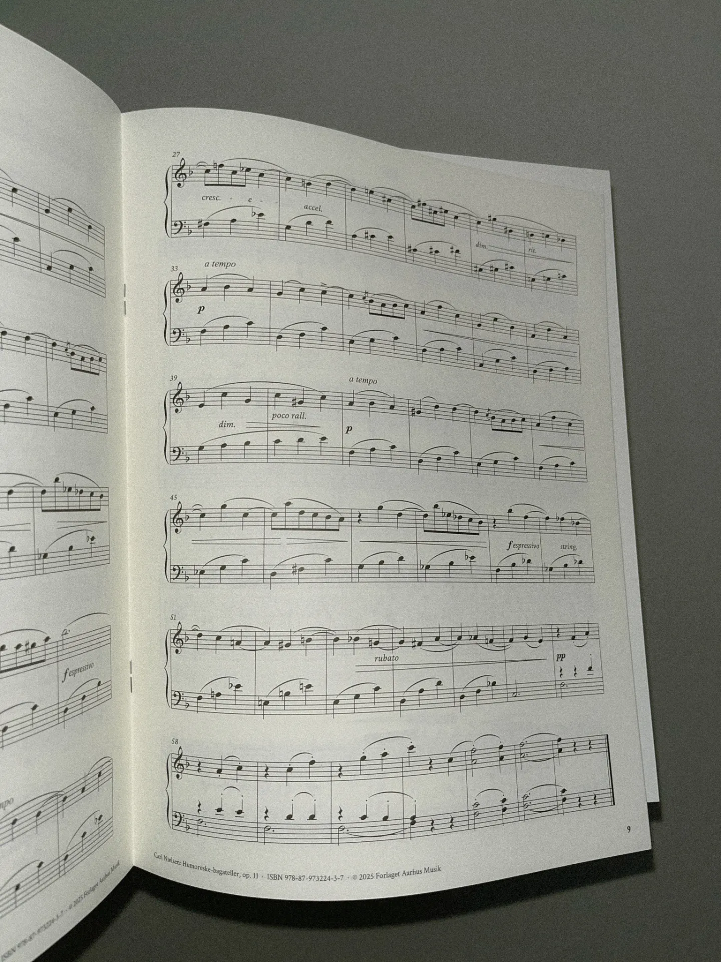 Open sheet music booklet showing page 9 of Carl Nielsen’s Humoresque Bagatelles, op. 11, with piano notation across six systems including markings such as cresc., a tempo, dim., rubato, and espressivo.