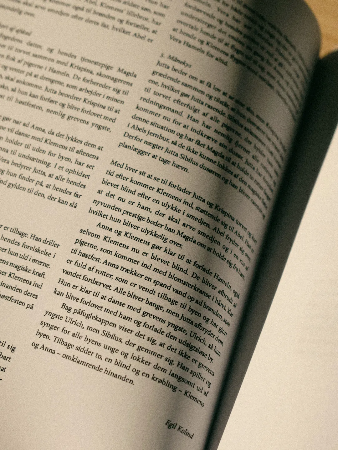 Angled book page with dense Danish text summarizing an opera plot, signed “Egil Kolind”