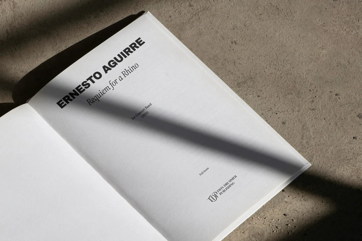 Printed score title page on concrete surface, strong shadows